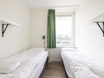 two beds in a room with a window at Lakehouse I in Uitgeest
