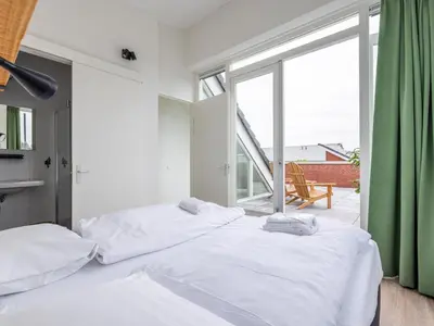 a bedroom with two beds and a large window at Lakehouse I in Uitgeest