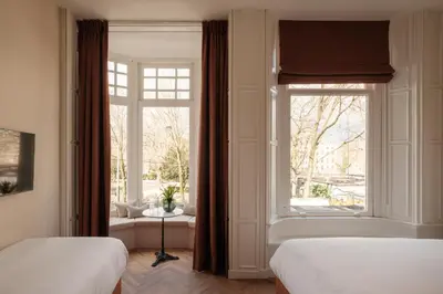 a bedroom with two beds and a large window at House of Adam in Amsterdam