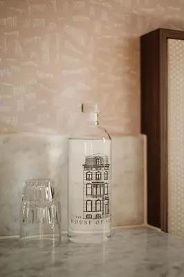 a bottle with a house on it sitting next to a glass at House of Adam in Amsterdam