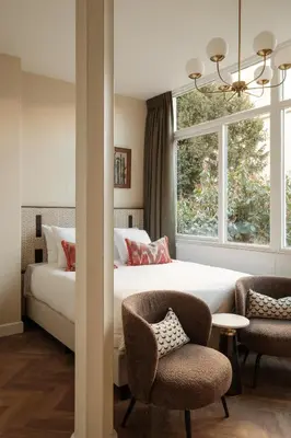 a bedroom with a bed and two chairs and a window at House of Adam in Amsterdam