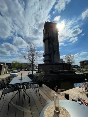 a patio with tables and chairs and a building at B&B De Tulpentoren in Roelofarendsveen