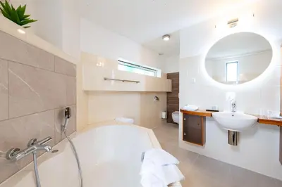 a white bathroom with a tub and a sink at B&B De Tulpentoren in Roelofarendsveen