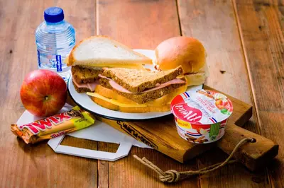 a sandwich on a plate on a wooden table with an apple at Campanile Hotel & Restaurant Amsterdam Zuid-Oost in Amsterdam