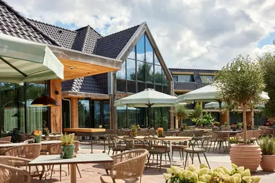 an outdoor restaurant with tables and chairs and umbrellas at Van der Valk Hotel Volendam - Recently renovated in Volendam