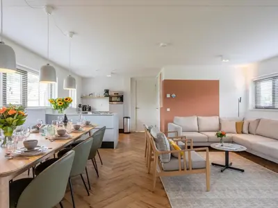 a dining room and living room with a long dining table at Holiday Home Pieper Luxe by Interhome in Noordwijk