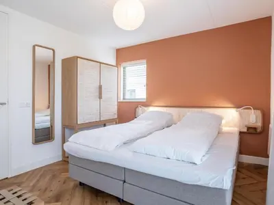a bedroom with a bed with white sheets and a mirror at Holiday Home Pieper Luxe by Interhome in Noordwijk