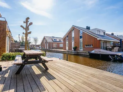 a wooden dock with a picnic table and a boat at Apartment Westergeest Luxe by Interhome in Uitgeest