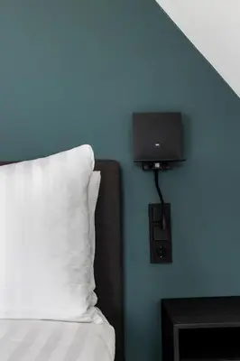 a bed with a pillow and a tv on a blue wall at Résidence Beaufort in Zandvoort