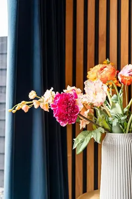 a vase filled with flowers in front of a curtain at Résidence Beaufort in Zandvoort