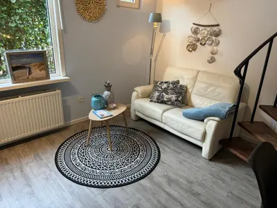 a living room with a couch and a table at Vakantiehuisje aan Zee met Dakterras Rust en Strand 250 m in Egmond aan Zee