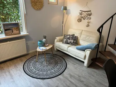 a living room with a couch and a table at Vakantiehuisje aan Zee met Dakterras Rust en Strand 250 m in Egmond aan Zee