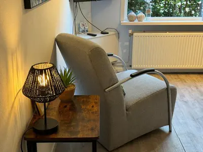 a living room with a chair and a lamp on a table at Vakantiehuisje aan Zee met Dakterras Rust en Strand 250 m in Egmond aan Zee