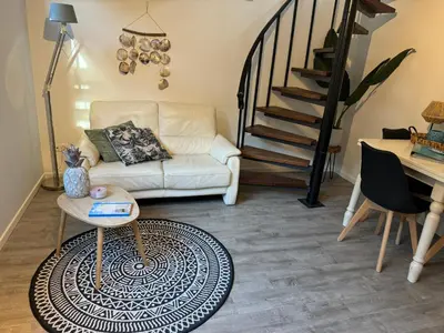 a living room with a white couch and a staircase at Vakantiehuisje aan Zee met Dakterras Rust en Strand 250 m in Egmond aan Zee