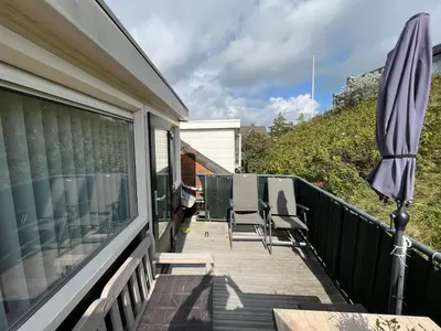 a balcony with an umbrella and chairs on a house at Vakantiehuisje aan Zee met Dakterras Rust en Strand 250 m in Egmond aan Zee