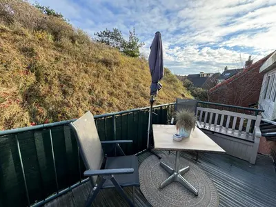 a table with an umbrella and a chair on a deck at Vakantiehuisje aan Zee met Dakterras Rust en Strand 250 m in Egmond aan Zee