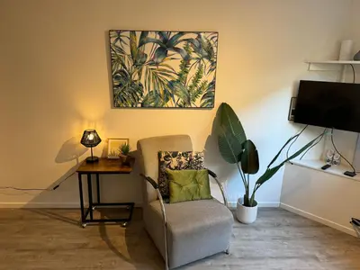 a living room with a chair and a desk and a painting at Vakantiehuisje aan Zee met Dakterras Rust en Strand 250 m in Egmond aan Zee