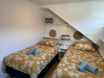 a bedroom with two beds and a staircase at Vakantiehuisje aan Zee met Dakterras Rust en Strand 250 m in Egmond aan Zee