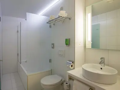 a white bathroom with a toilet and a sink at Hotel Woudschoten in Zeist