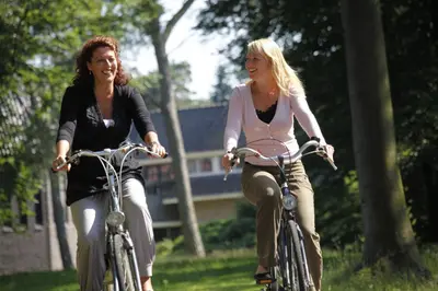 two women riding bikes in a park at Hotel Woudschoten in Zeist