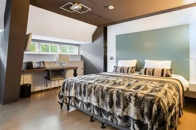 a bedroom with a bed and a desk in it at Hotel Woudschoten in Zeist