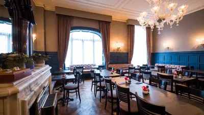 a restaurant with tables and chairs and a chandelier at Hotel Aalders in Amsterdam