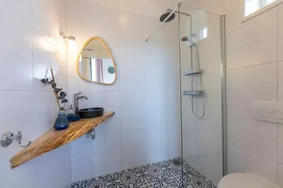 a bathroom with a shower and a sink and a mirror at De Boterhal - vakantiehuisje op natuurboerderij in Hem