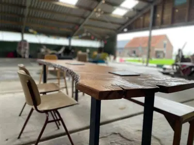 a wooden table and two chairs in a warehouse at De Boterhal - vakantiehuisje op natuurboerderij in Hem