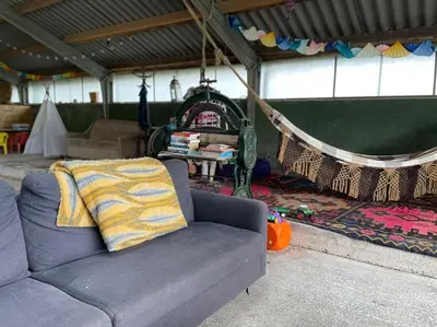 a living room with a couch and a hammock at Groepsaccommodatie op natuurboerderij Huize Blokland in Hem