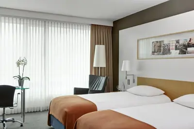 a hotel room with two beds and a desk at Steigenberger Airport Hotel Amsterdam in Schiphol