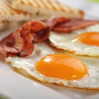 two fried eggs and bacon on a white plate at Steigenberger Airport Hotel Amsterdam in Schiphol