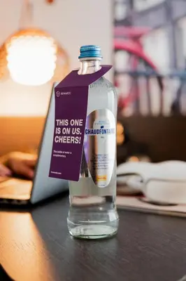 a bottle of water sitting on a table next to a laptop at Steigenberger Airport Hotel Amsterdam in Schiphol
