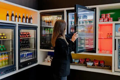 a woman is looking inside of a refrigerator at Steigenberger Airport Hotel Amsterdam in Schiphol