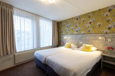 a bedroom with a large bed and a large window at Hotel de Magneet in Hoorn