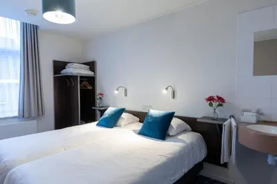 a hotel room with two beds and a sink at Hotel de Magneet in Hoorn
