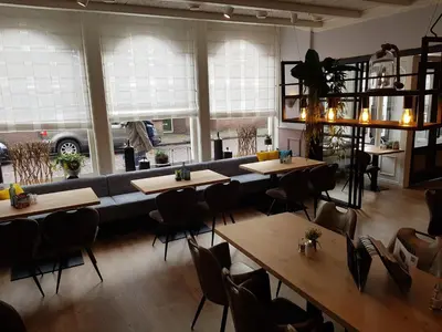 a restaurant with tables and a couch and windows at Hotel de Magneet in Hoorn