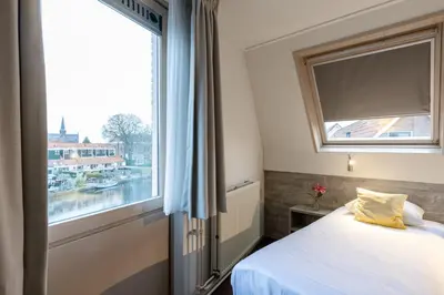 a bedroom with a bed and a large window at Hotel de Magneet in Hoorn