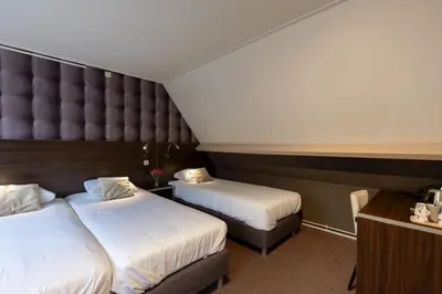 a hotel room with two beds and a large headboard at Hotel de Magneet in Hoorn