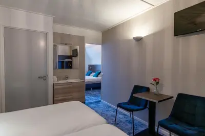a hotel room with a bed and two blue chairs at Hotel de Magneet in Hoorn