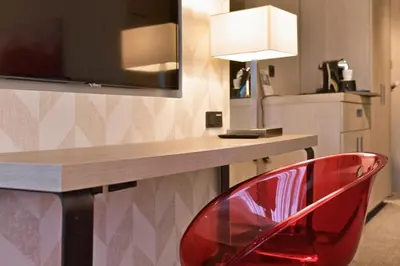 a red chair in front of a desk with a television at Van der Valk Hotel de Bilt-Utrecht in De Bilt
