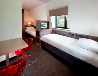 a hotel room with two beds and a table and chairs at Van der Valk Hotel de Bilt-Utrecht in De Bilt