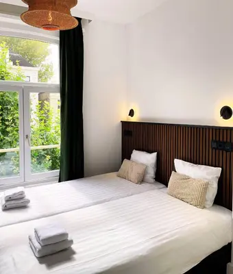 a bedroom with a large bed with a large window at Hotel Plantage in Amsterdam