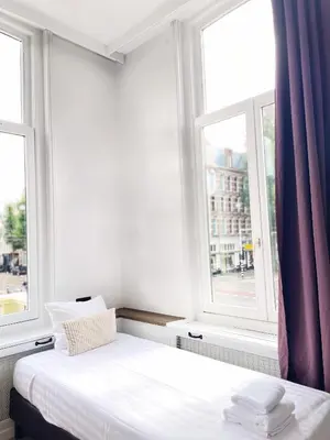 a bed in a room with two windows at Hotel Plantage in Amsterdam