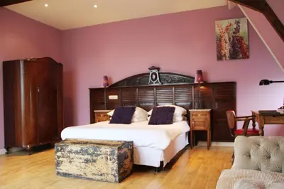 a bedroom with a large bed with a wooden headboard at Augusta Hotel in IJmuiden
