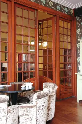 a dining room with chairs and a table and glass doors at Augusta Hotel in IJmuiden