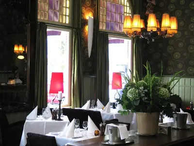 a dining room with tables with white table cloth at Augusta Hotel in IJmuiden