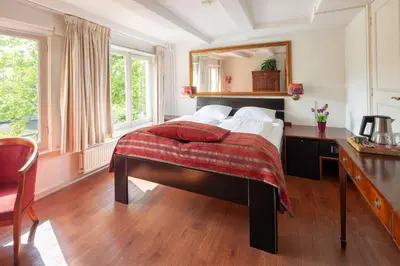 a bedroom with a bed with a desk and a mirror at Amsterdam House Hotel in Amsterdam