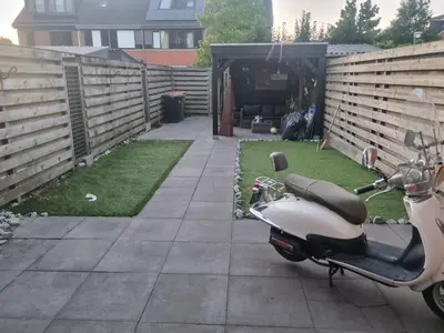 a scooter parked in a yard next to a fence at Leuke tussenwoning in Hoogkarspel