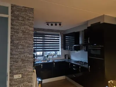 a kitchen with black appliances and a brick wall at Leuke tussenwoning in Hoogkarspel