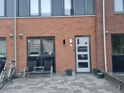 a brick building with two chairs and a door at Leuke tussenwoning in Hoogkarspel